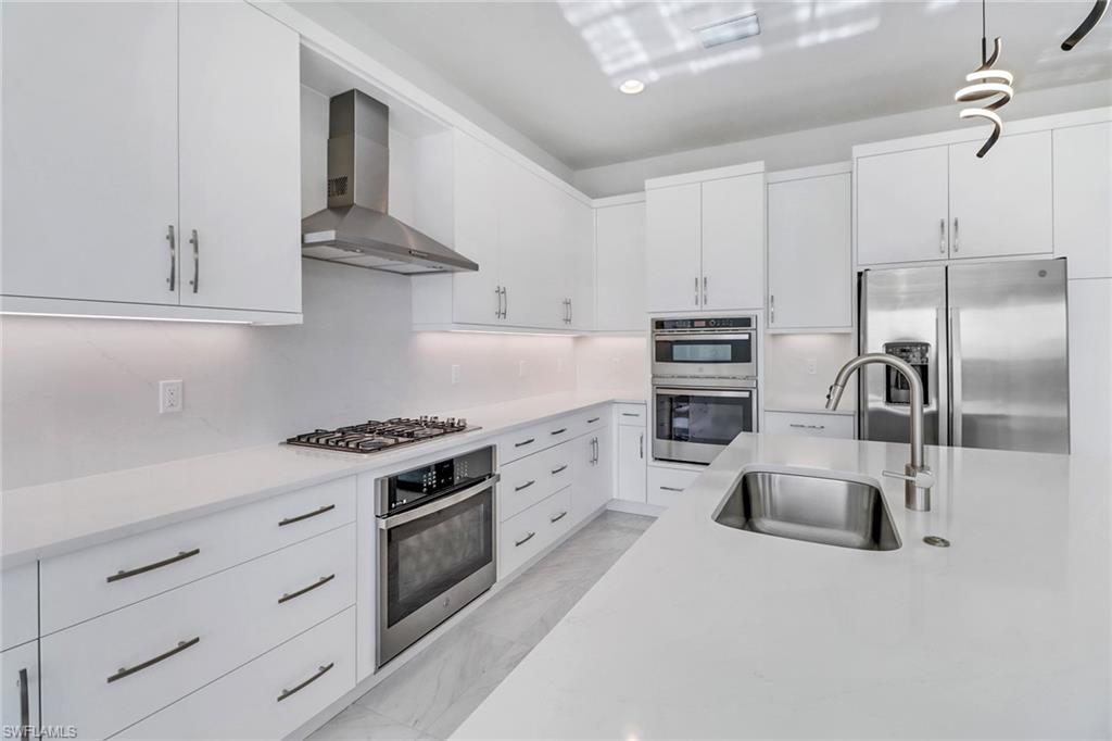 20458 Fair Oak Lane Estero, FL 33928 - Photo 10 of 40 Kitchen featuring sink, wall chimney exhaust hood, pendant lighting, white cabinets, and appliances with stainless steel finishes