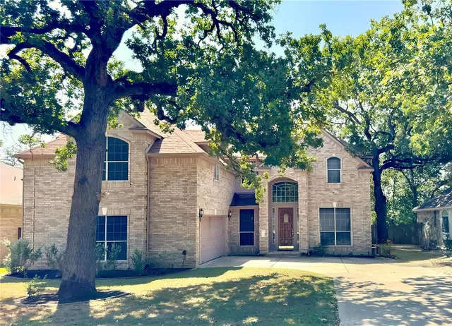 a view of a yard in front of a house with large tree