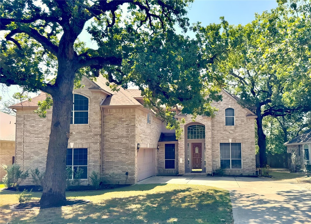 a view of a yard in front of a house with large tree