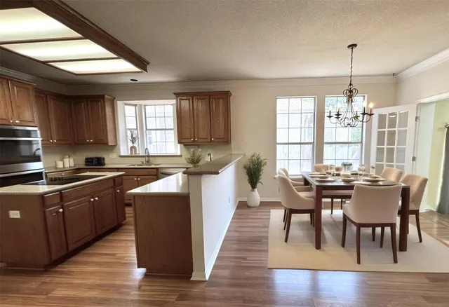 a kitchen with stainless steel appliances granite countertop wooden floors stove dining table and chairs