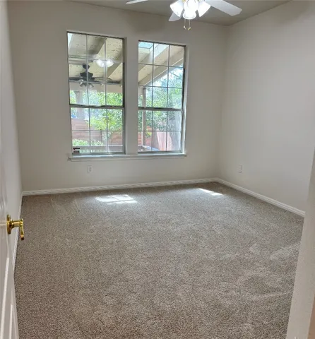 an empty room with windows and chandelier fan