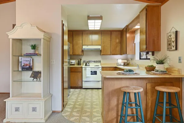 a kitchen with kitchen island granite countertop wooden cabinets and white appliances
