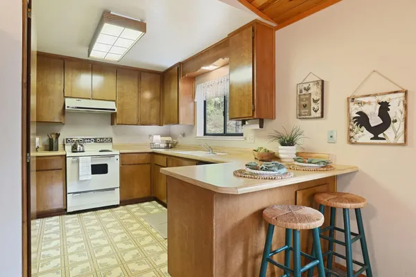 a kitchen with stainless steel appliances kitchen island granite countertop a sink a stove a table and chairs