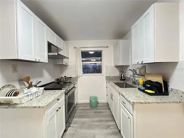 a kitchen with granite countertop a sink a stove and cabinets