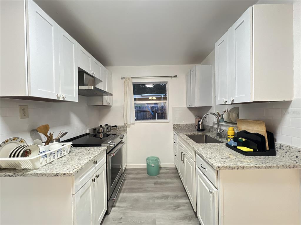 902 San Domingo Road Orlando, FL 32808 - Photo 11 of 18 a kitchen with granite countertop a sink a stove and cabinets