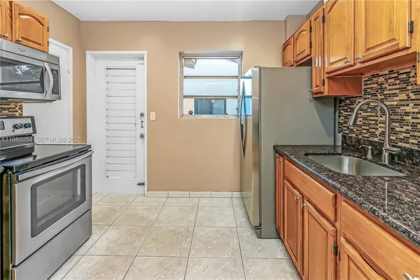 a kitchen with granite countertop a stove a sink and a refrigerator