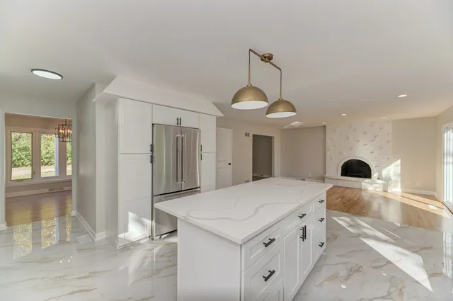 a large white kitchen with a refrigerator a sink and a fireplace