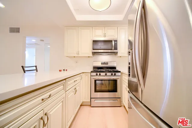 a kitchen with stainless steel appliances granite countertop white cabinets and a stove top oven