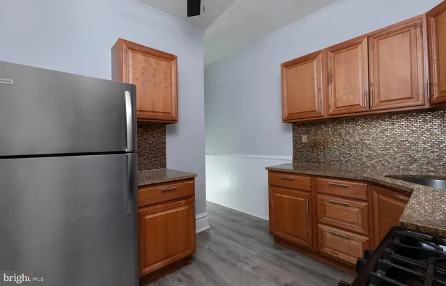 a kitchen with granite countertop wooden cabinets and a refrigerator
