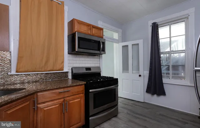 a kitchen with granite countertop stainless steel appliances a stove microwave and refrigerator