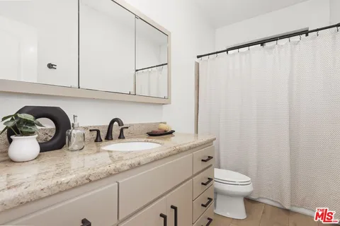 a bathroom with a granite countertop sink a toilet and vanity