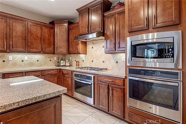 a kitchen with stainless steel appliances granite countertop a table chairs and a refrigerator