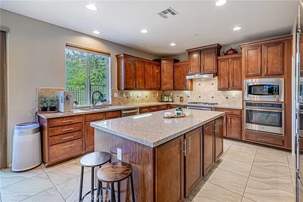 a kitchen with stainless steel appliances granite countertop wooden cabinets a sink and dishwasher with wooden floor