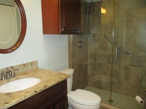 a bathroom with a granite countertop sink a toilet and shower