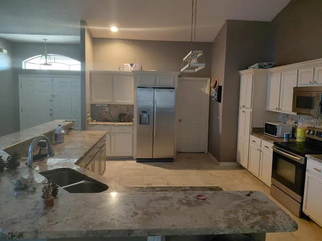 a kitchen with stainless steel appliances kitchen island granite countertop a sink refrigerator and cabinets