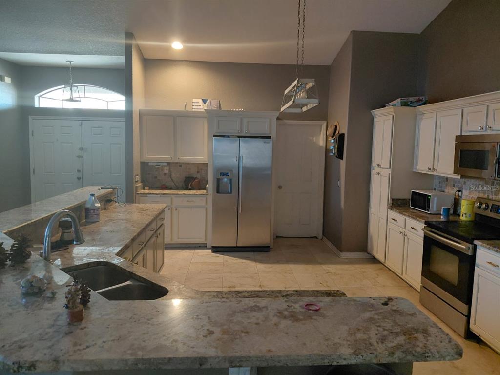 11382 Mahopac Road Weeki Wachee, FL 34614 - Photo 6 of 35 a kitchen with stainless steel appliances kitchen island granite countertop a sink refrigerator and cabinets