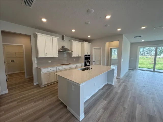 a large kitchen with stainless steel appliances granite countertop a lot of counter space and wooden floors