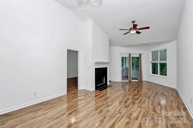 a view of a livingroom with a fireplace a ceiling fan and wooden floor