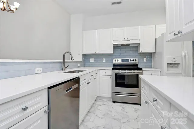 a kitchen with granite countertop white cabinets and white appliances