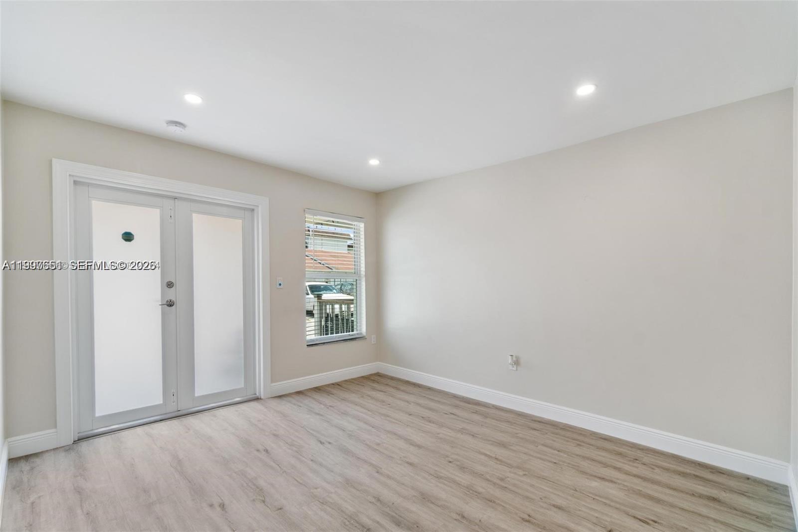 330 West 74th Place, Unit 330 Hialeah, FL 33014 - Photo 29 of 31 an empty room with wooden floor and windows