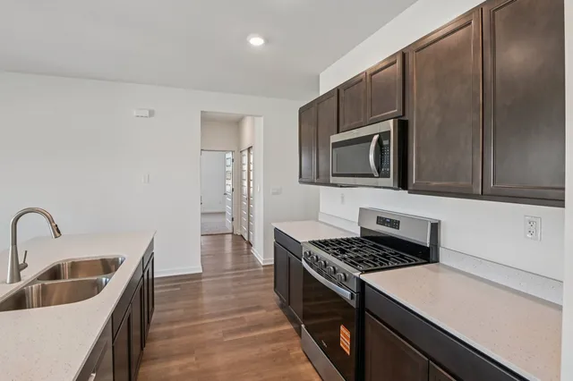 a kitchen with a sink a stove top oven and wooden floor