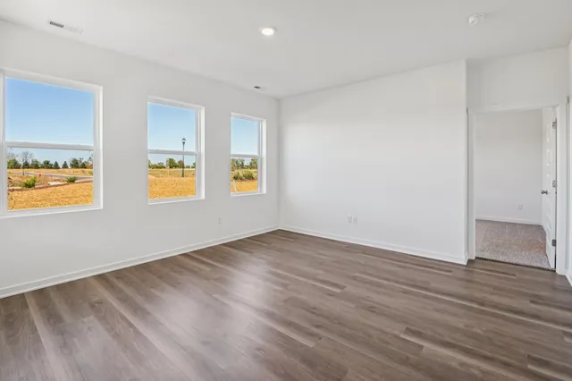 a view of an empty room with window and wooden floor