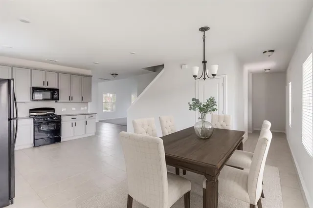 a kitchen with stainless steel appliances granite countertop a stove a refrigerator a kitchen island a sink dishwasher a dining table and chairs with wooden floor