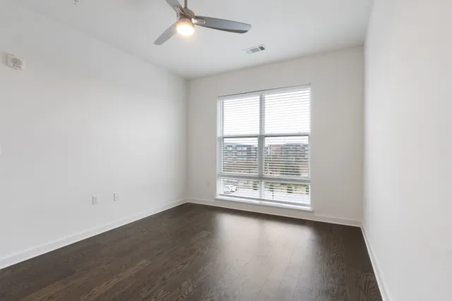 an empty room with wooden floor and ceiling fan
