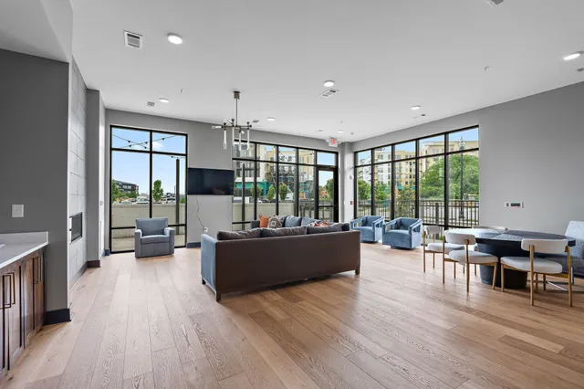 a living room with furniture large window and wooden floor