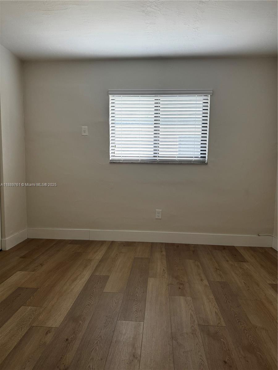 1330 West 29th Street, Unit 30 Hialeah, FL 33012 - Photo 7 of 13 an empty room with wooden floor and windows