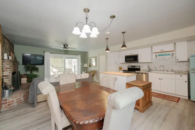 a kitchen with stainless steel appliances kitchen island granite countertop a stove a sink a dining table and chairs with wooden floor