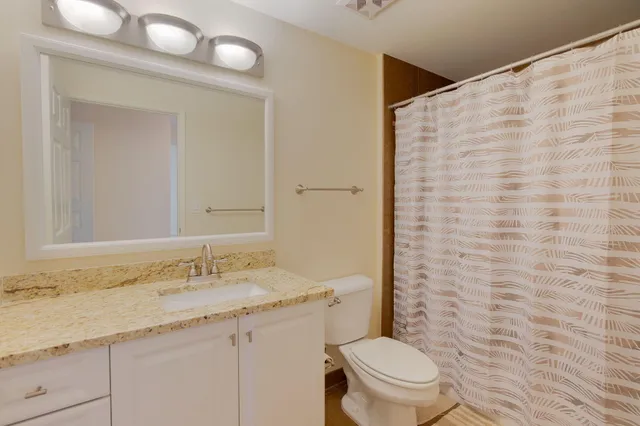 a bathroom with a granite countertop sink a toilet and a mirror