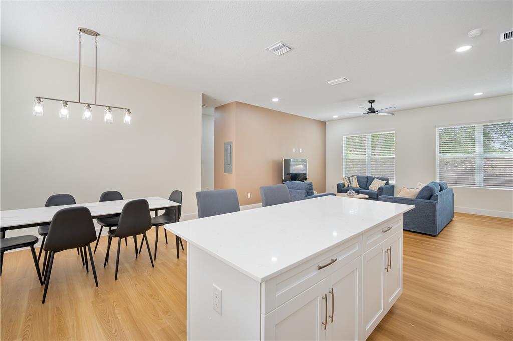 13614 North 22nd Street Tampa, FL 33613 - Photo 16 of 30 a large white kitchen with a dining table chairs and wooden floor