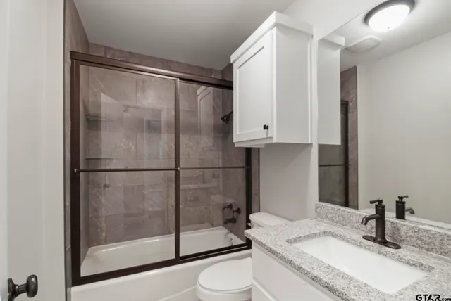 a bathroom with a granite countertop sink toilet and shower