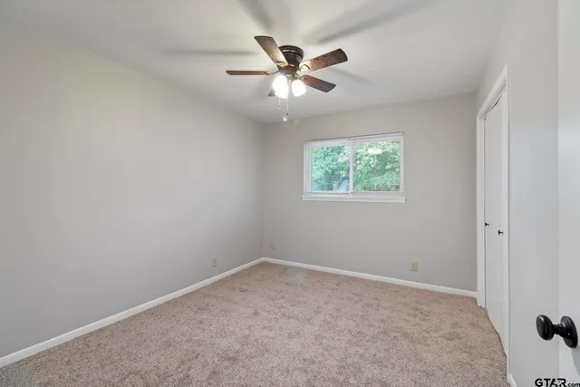an empty room with a window and a fan
