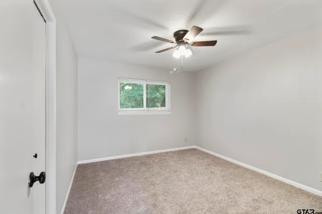 an empty room with windows and fan