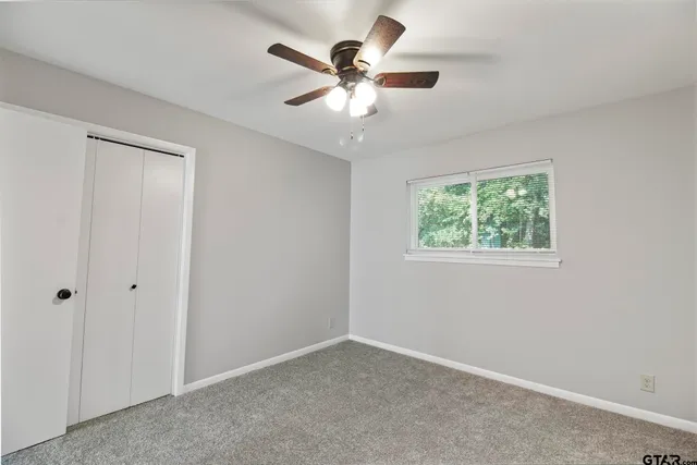 an empty room with a window and a ceiling fan