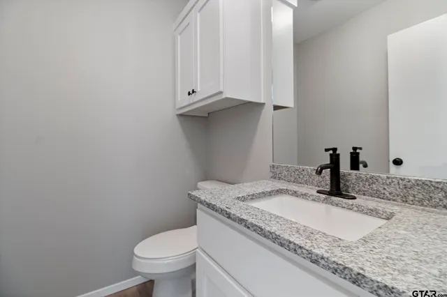 a bathroom with a granite countertop toilet and sink