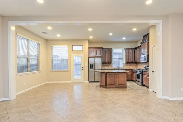 a large kitchen with stainless steel appliances kitchen island granite countertop a large counter top and a stove top oven
