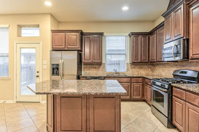 a kitchen with stainless steel appliances granite countertop a sink stove and refrigerator