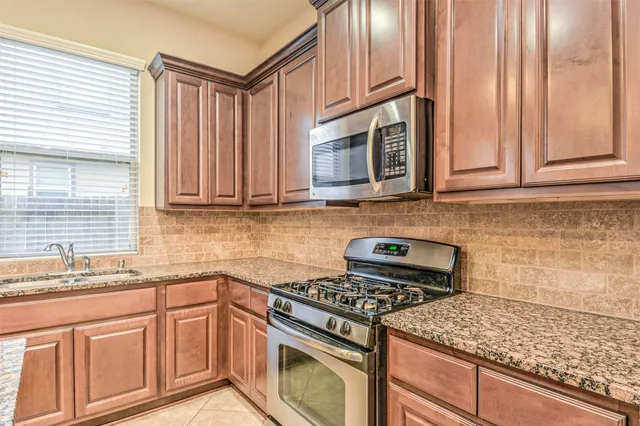a kitchen with stainless steel appliances granite countertop a stove a sink and a microwave