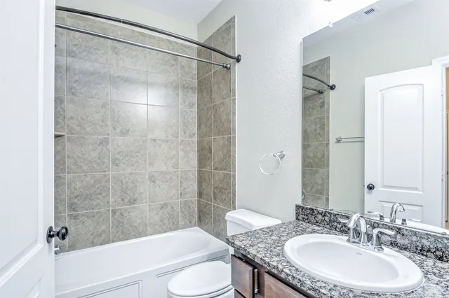 a bathroom with a granite countertop sink toilet and shower