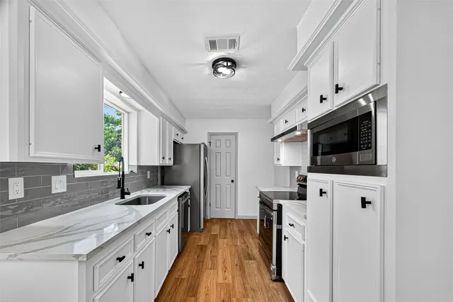 a kitchen with stainless steel appliances a stove microwave and a sink
