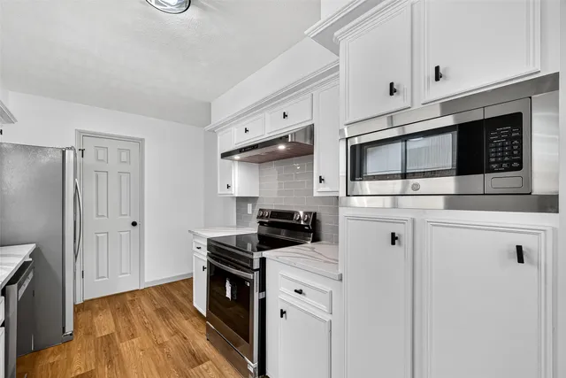 a kitchen with stainless steel appliances a stove a microwave and cabinets