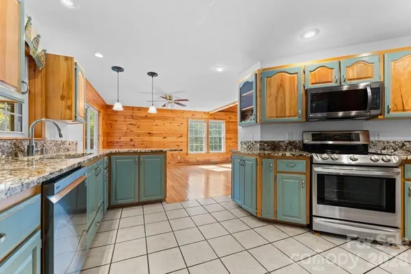 a kitchen with stainless steel appliances granite countertop a stove a sink and a microwave