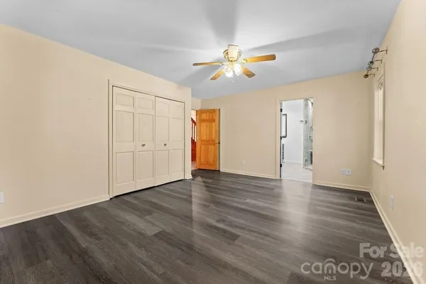 an empty room with wooden floor closet and windows
