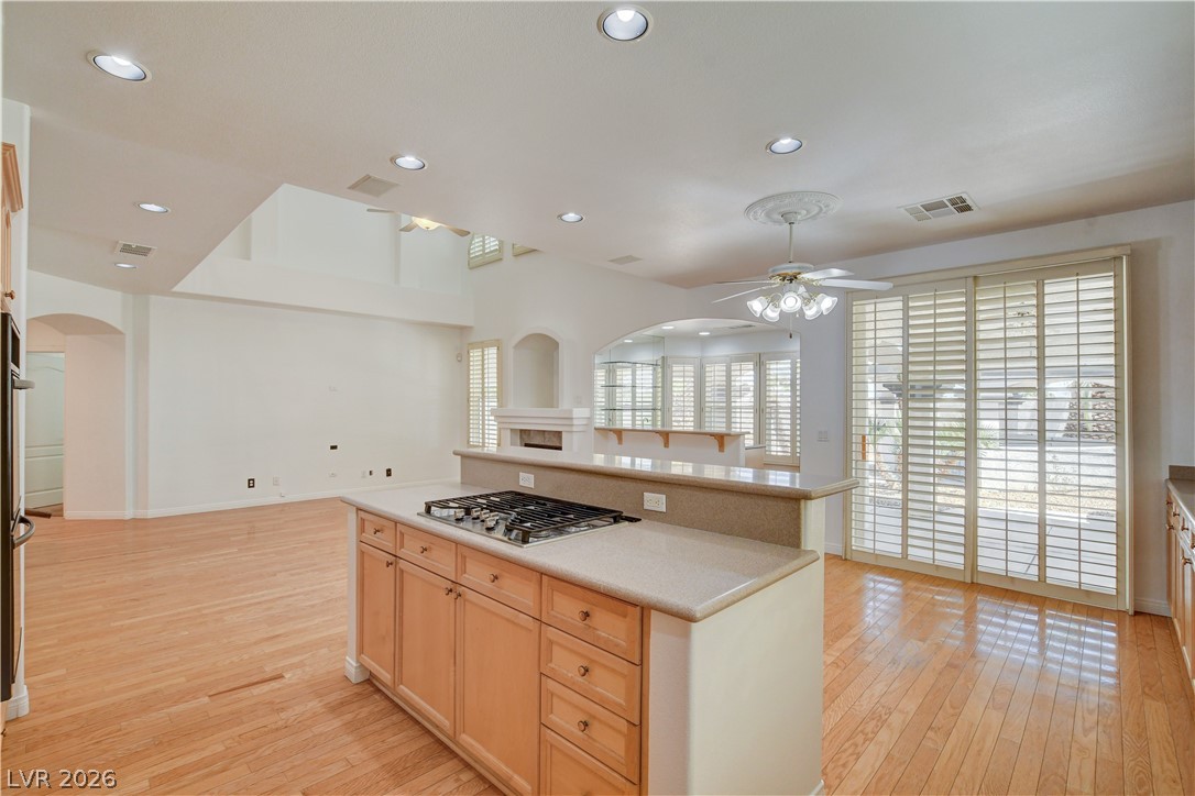 4354 Tall Tree Street Las Vegas, NV 89147 - Photo 25 of 67 This kitchen and living area features a gas cooktop island and warm wood flooring.