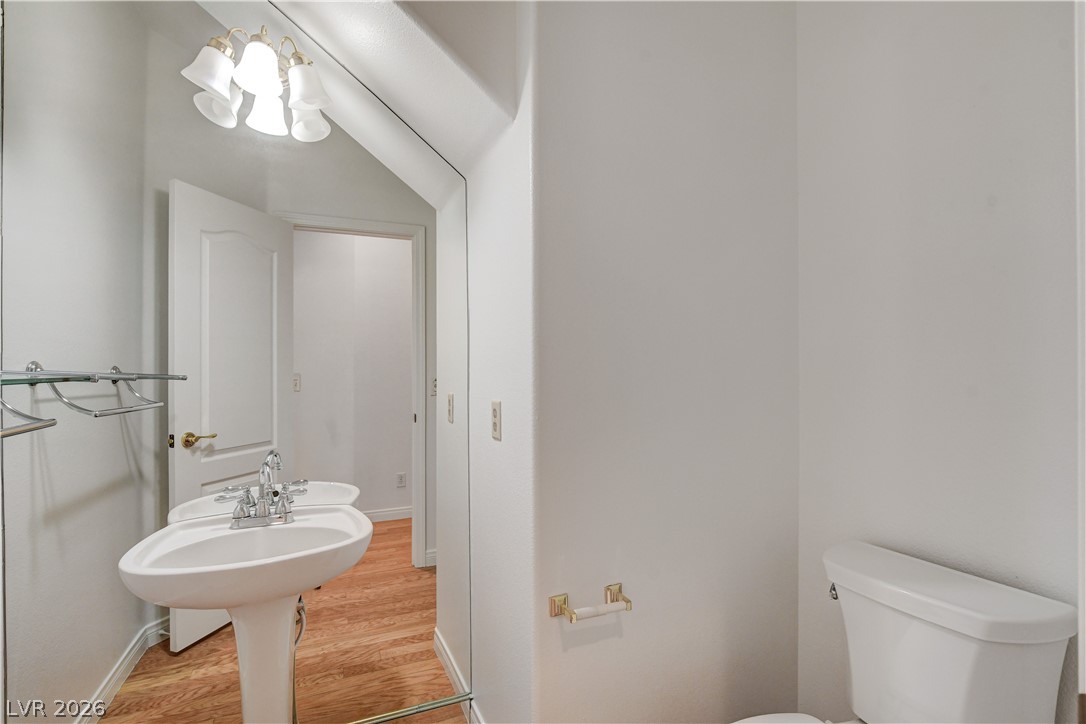 4354 Tall Tree Street Las Vegas, NV 89147 - Photo 28 of 67 This bright bathroom features warm wood flooring and a classic pedestal sink, offering a clean, simple aesthetic.