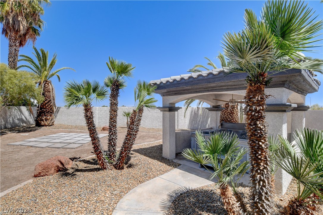 4354 Tall Tree Street Las Vegas, NV 89147 - Photo 66 of 67 This desert landscape features mature palms, a shaded patio, and a paver stone area, ideal for outdoor gatherings.