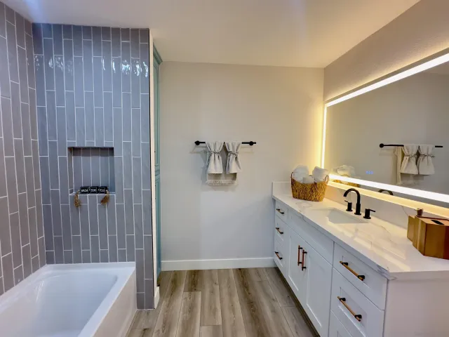 a bathroom with a granite countertop sink a mirror and bathtub